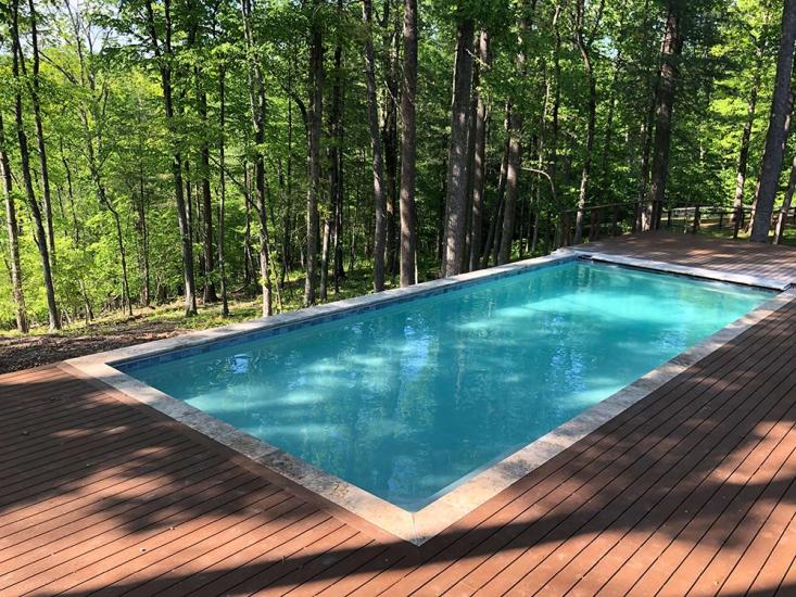 Pool with deck near wooded area